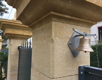 fixation d'une cloche de portail en bronze près de la porte